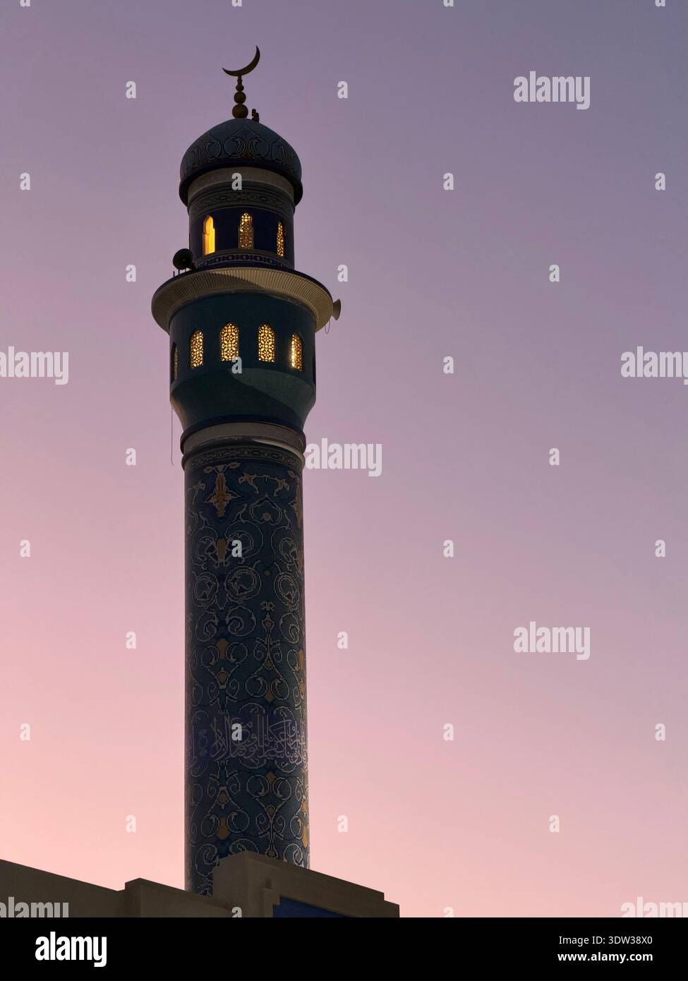 Illuminated mosque with crescent moon symbol at dusk in Muscat, Oman - Smartphone Captured Stock Image