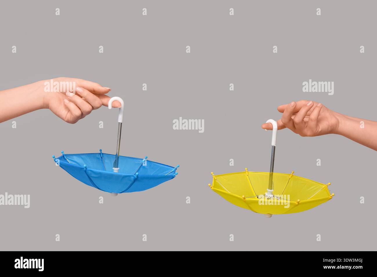 Female hands with different mini umbrellas on grey background Stock Photo