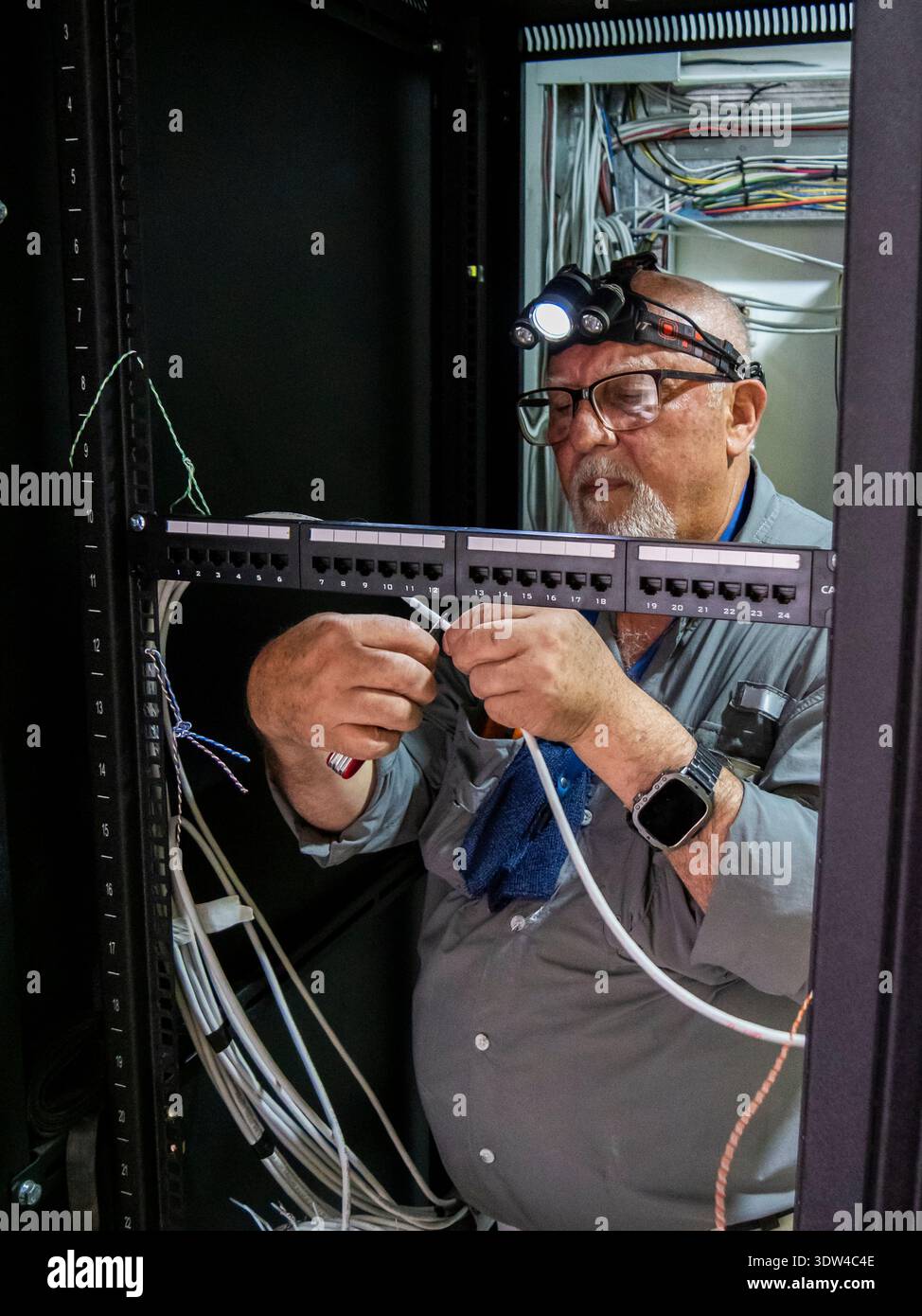 Adult technician working inside a server rack cabinet connecting and ...