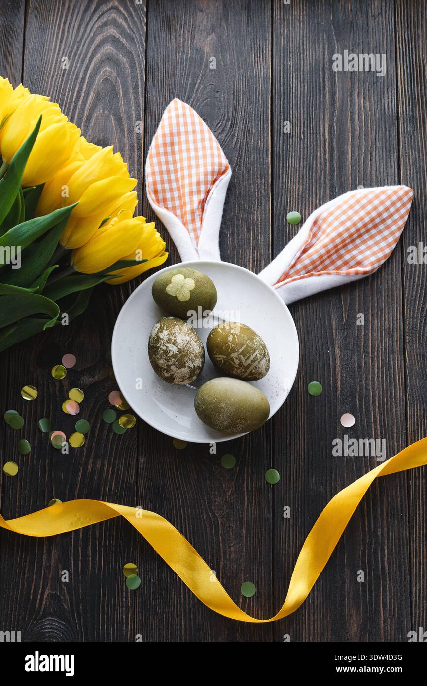 Easter flat lay composition with yellow tulips, natural dyed Easter eggs Stock Photo