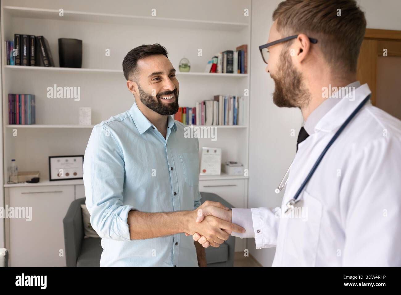 Two smiling young men doctor and pharma representative shake hands Stock Photo