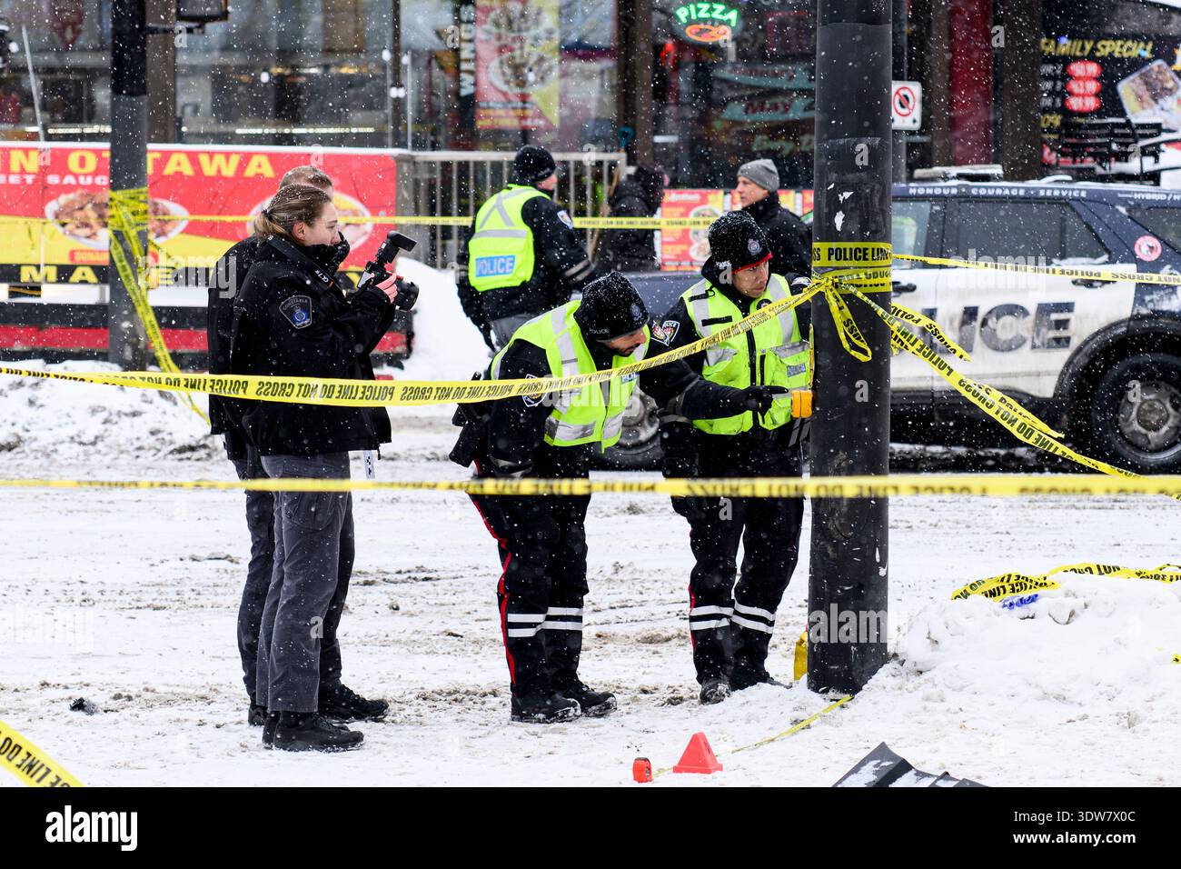 Officers from the Ottawa Police Service (OPS) inspect a traffic pole as ...