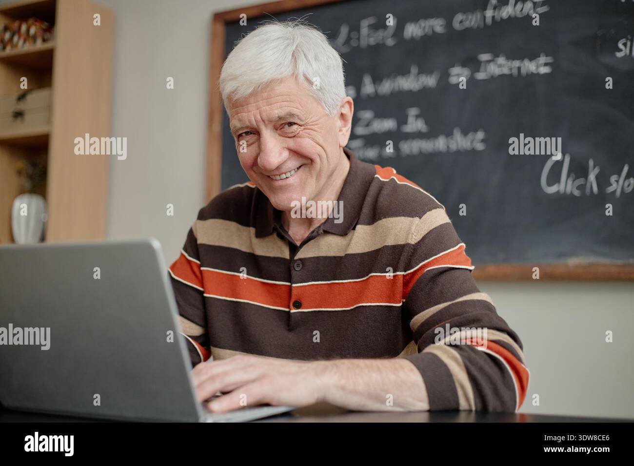 Senior Caucasian Man Smiling While Using Laptop during Educational Activity Stock Photo