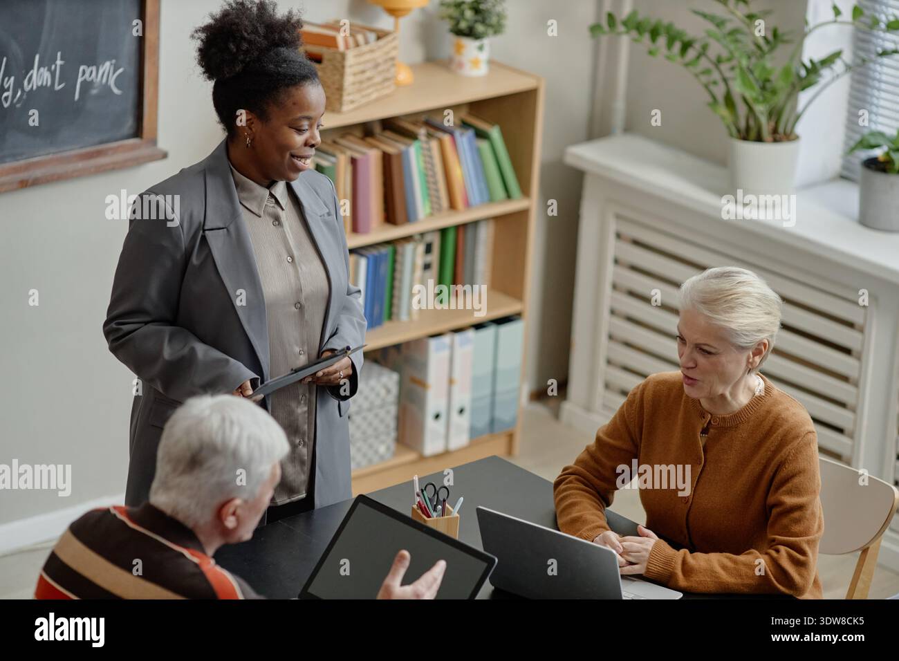 Young Adult Black Woman Teaching Middle Aged Caucasian People in Classroom Stock Photo