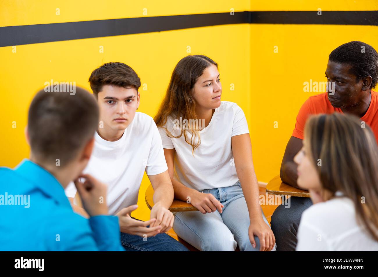 Friendly adult students chatting cheerfully while sitting in classroom Stock Photo