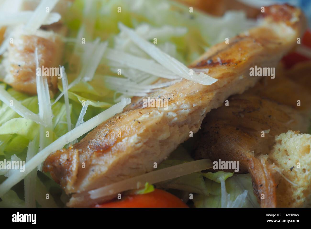 Fresh salad with grilled chicken and cheese strips on top Stock Photo