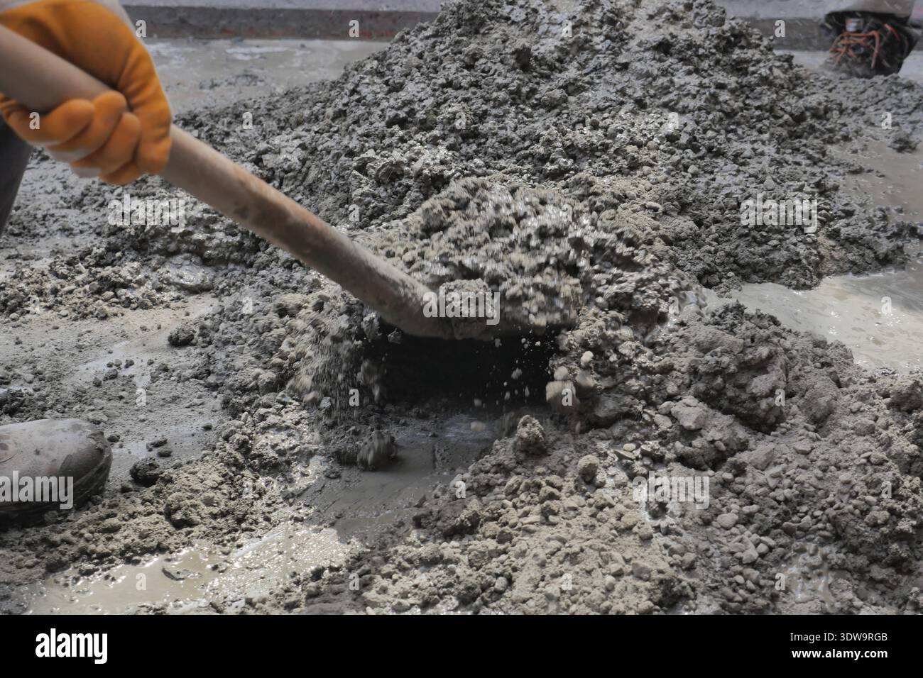 Construction worker mixes cement on a job site Stock Photo