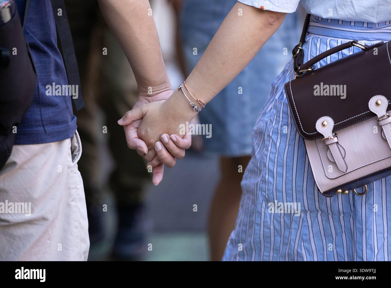 Couple holding hands walking in market, people interacting in public ...
