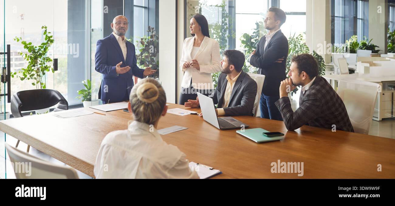 Business leader speaking on office meeting in front of diverse team of employees Stock Photo