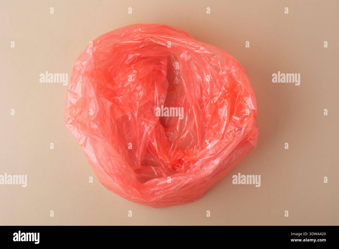 Red crumpled plastic bag representing waste and environmental pollution Stock Photo