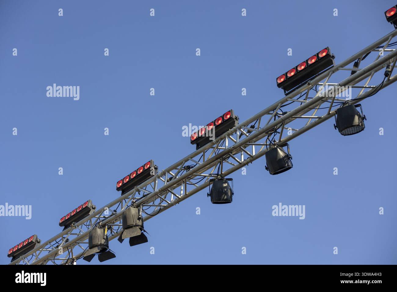Outdoor stage lighting equipment on metal truss under clear blue sky. Professional setup for concert or event creating anticipation for big show Stock Photo