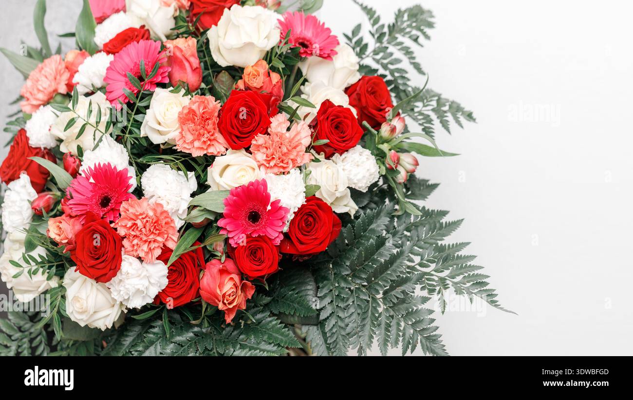 Romantic large bouquet flowers on light background. Red and ivory rose, coral carnation, pink gerbera daisy flowers and fern leaves Stock Photo