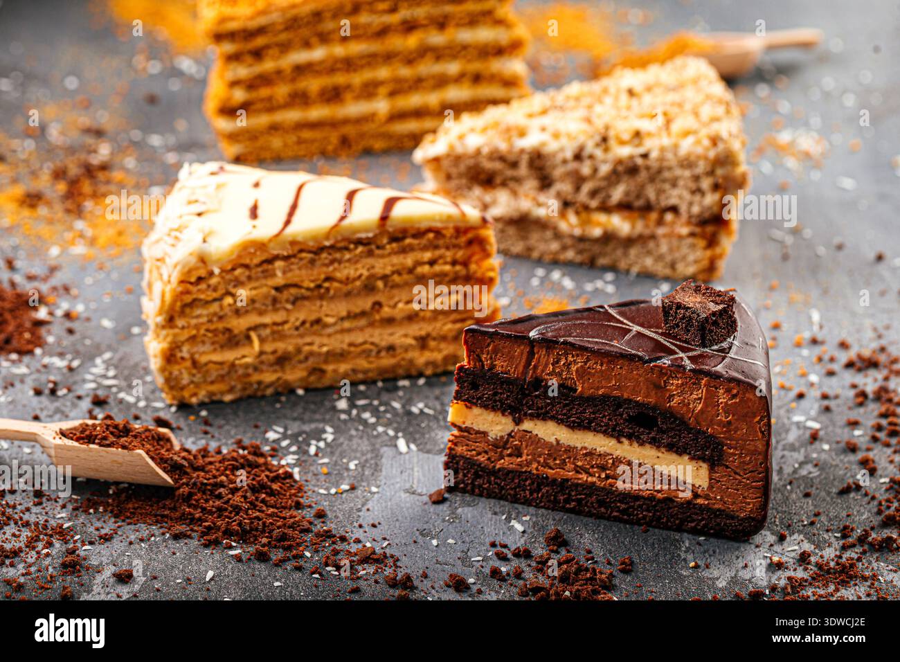Assorted layered cake slices on dark table Stock Photo