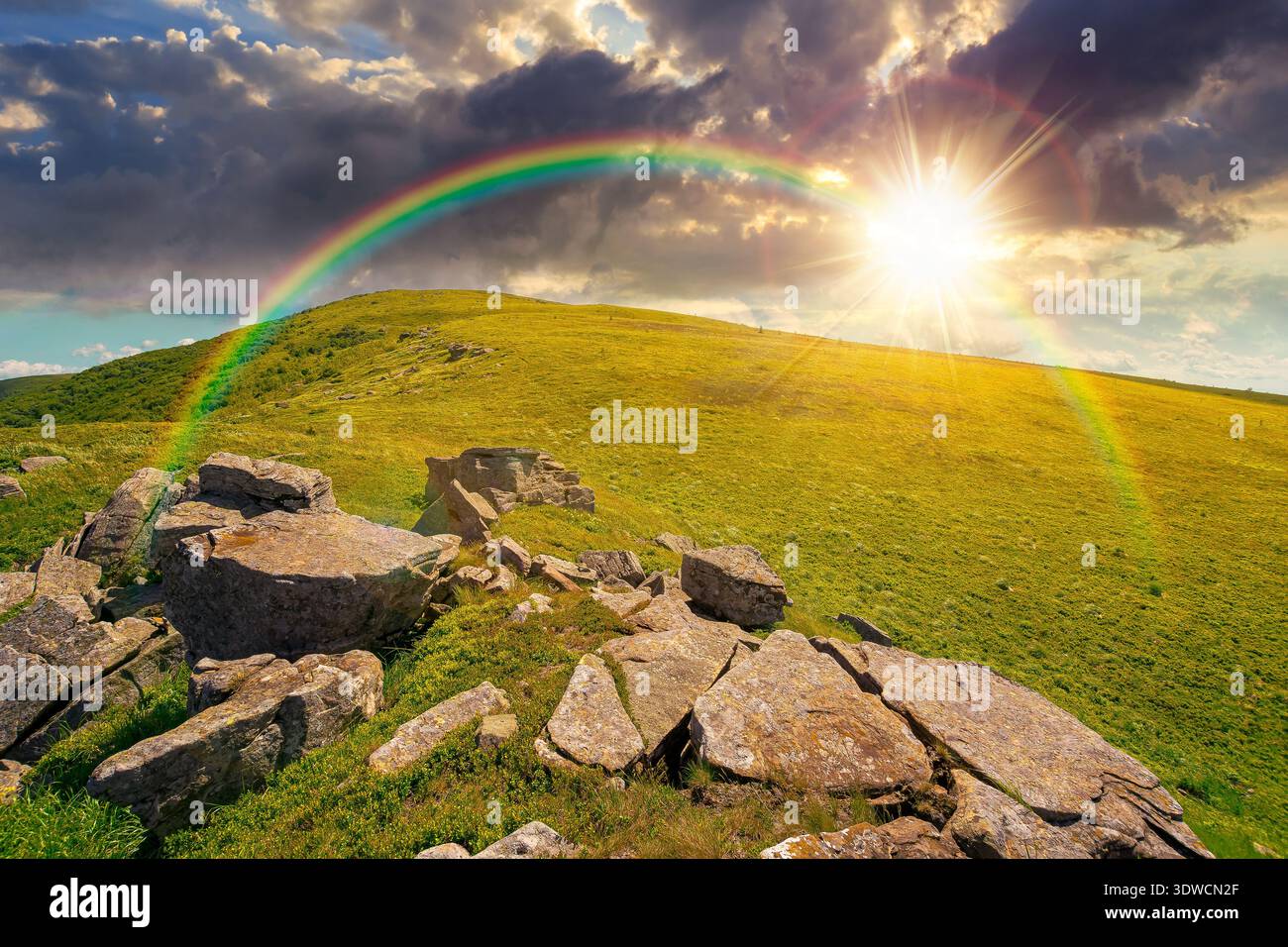 sunset over rocks and rolling hills in mountain landscape in summer. scenery with green grass on alpine meadow under sky with clouds. background for r Stock Photo
