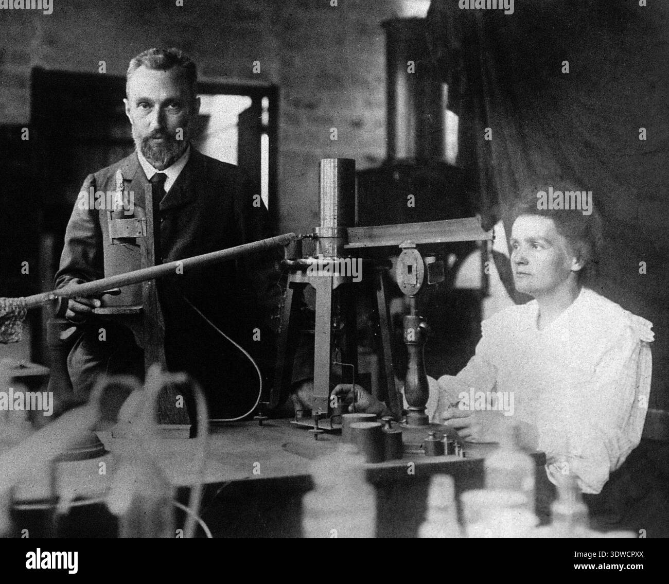 This vintage photographic capture from 1904 shows Nobel laureates Pierre and Marie Skłodowska-Curie in their laboratory. They are depicted with scientific equipment, likely conducting experiments related to their pioneering work on radioactivity. Stock Photo