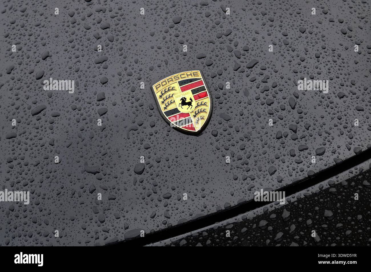 raindrops on black porsche sports car bonnet Stock Photo