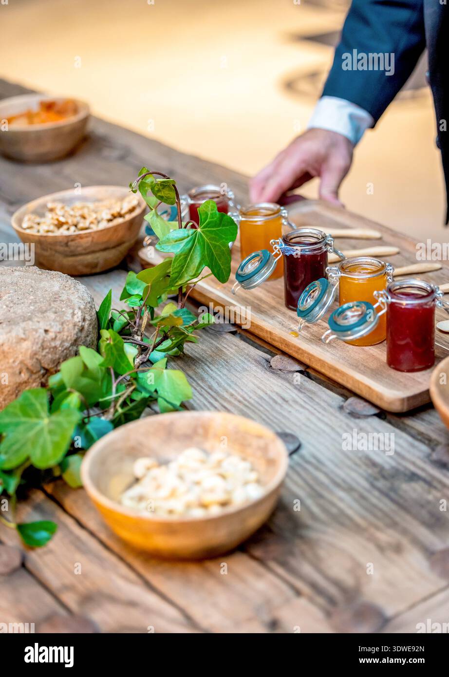 An elegant display of assorted jams, dried fruits, and nuts on a rustic table, perfect for enhancing gourmet experiences in fine dining and culinary p Stock Photo