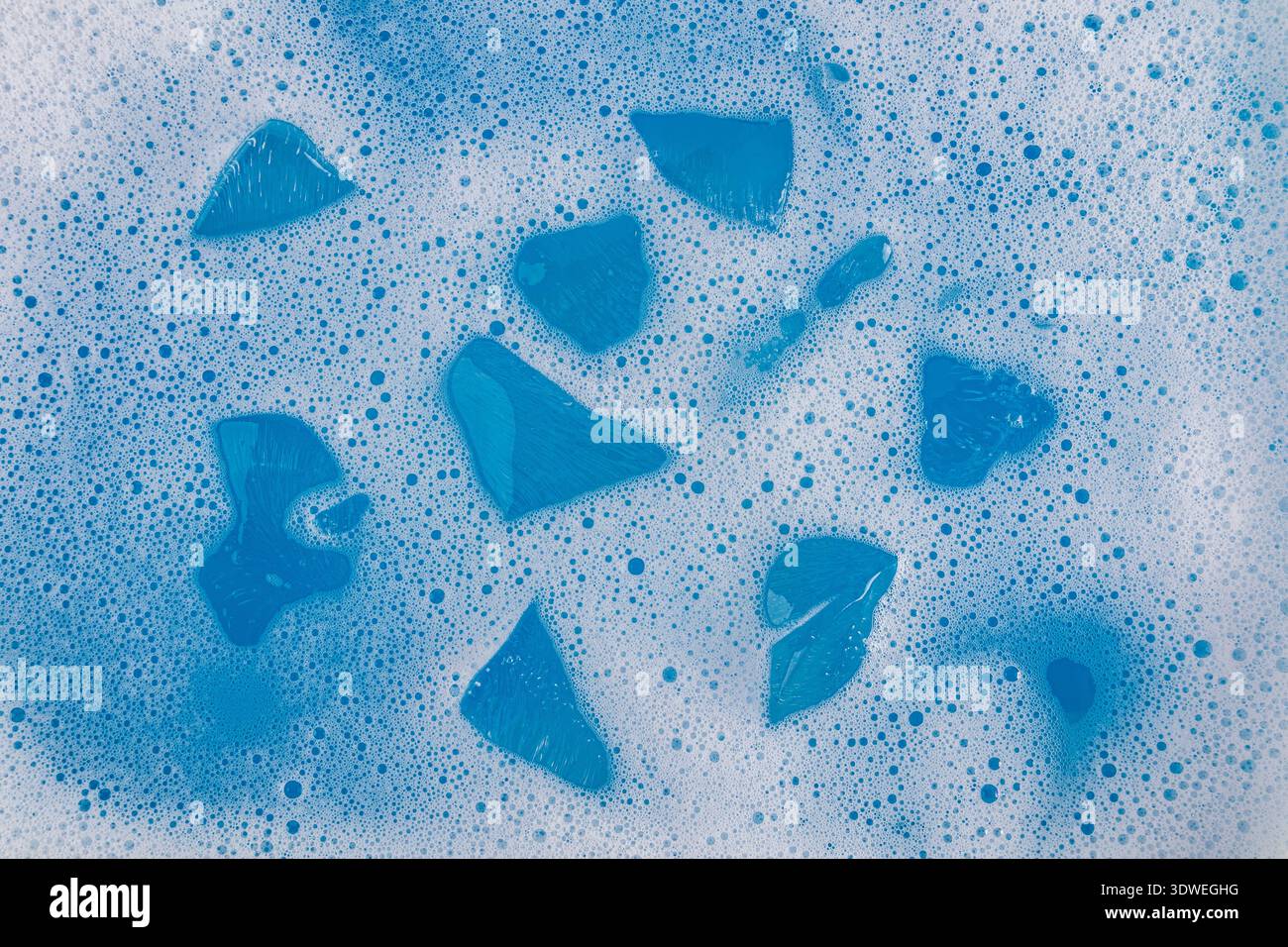 Blue ice cubes rest gently within a frothy sea of blue matcha bubbles, creating a refreshing and calming visual. The cool tones evoke a sense of tranq Stock Photo