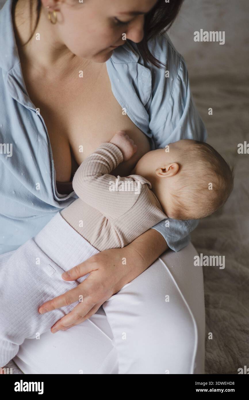 A nurturing scene of a mother tenderly breastfeeding her newborn in a tranquil environment, symbolizing the essence of motherly love, care, and connec Stock Photo