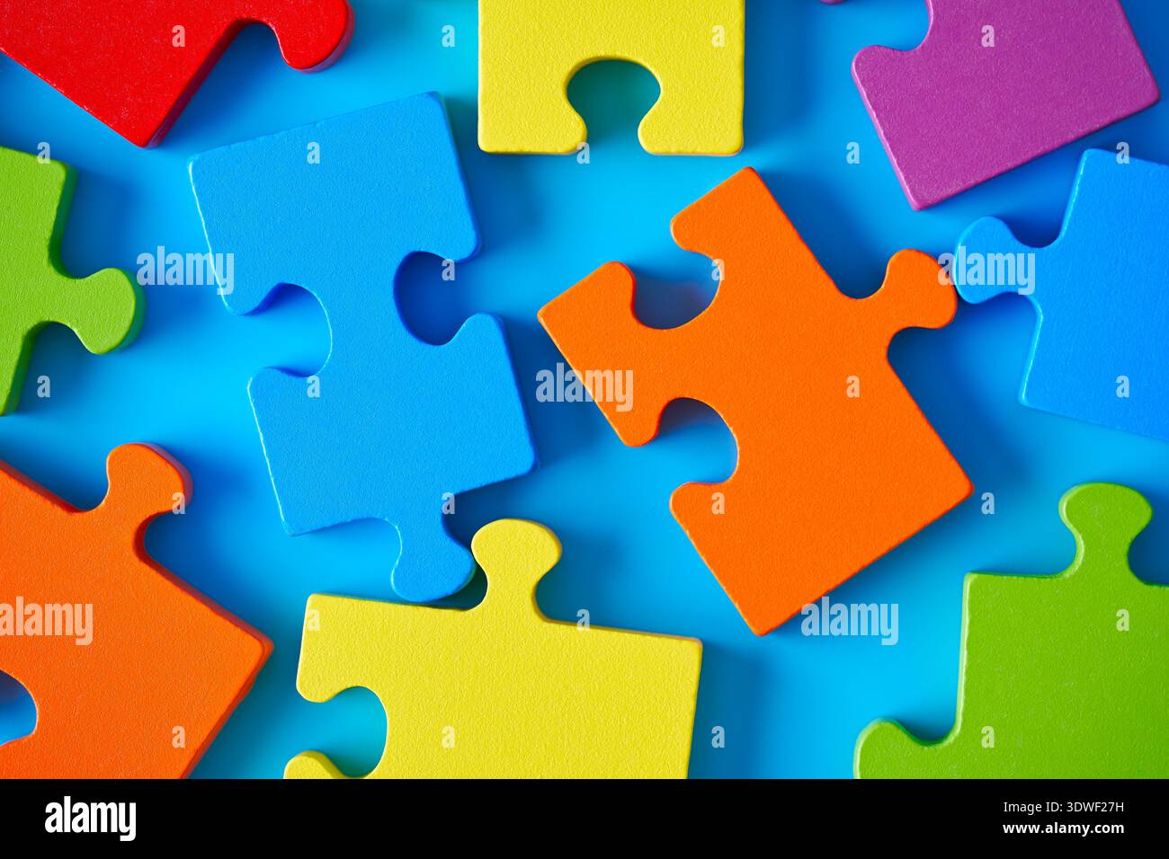 Vibrant jigsaw puzzle pieces scattered on a blue surface symbolizing autism and mental development. The pieces represent complexity, strategy, and bra Stock Photo