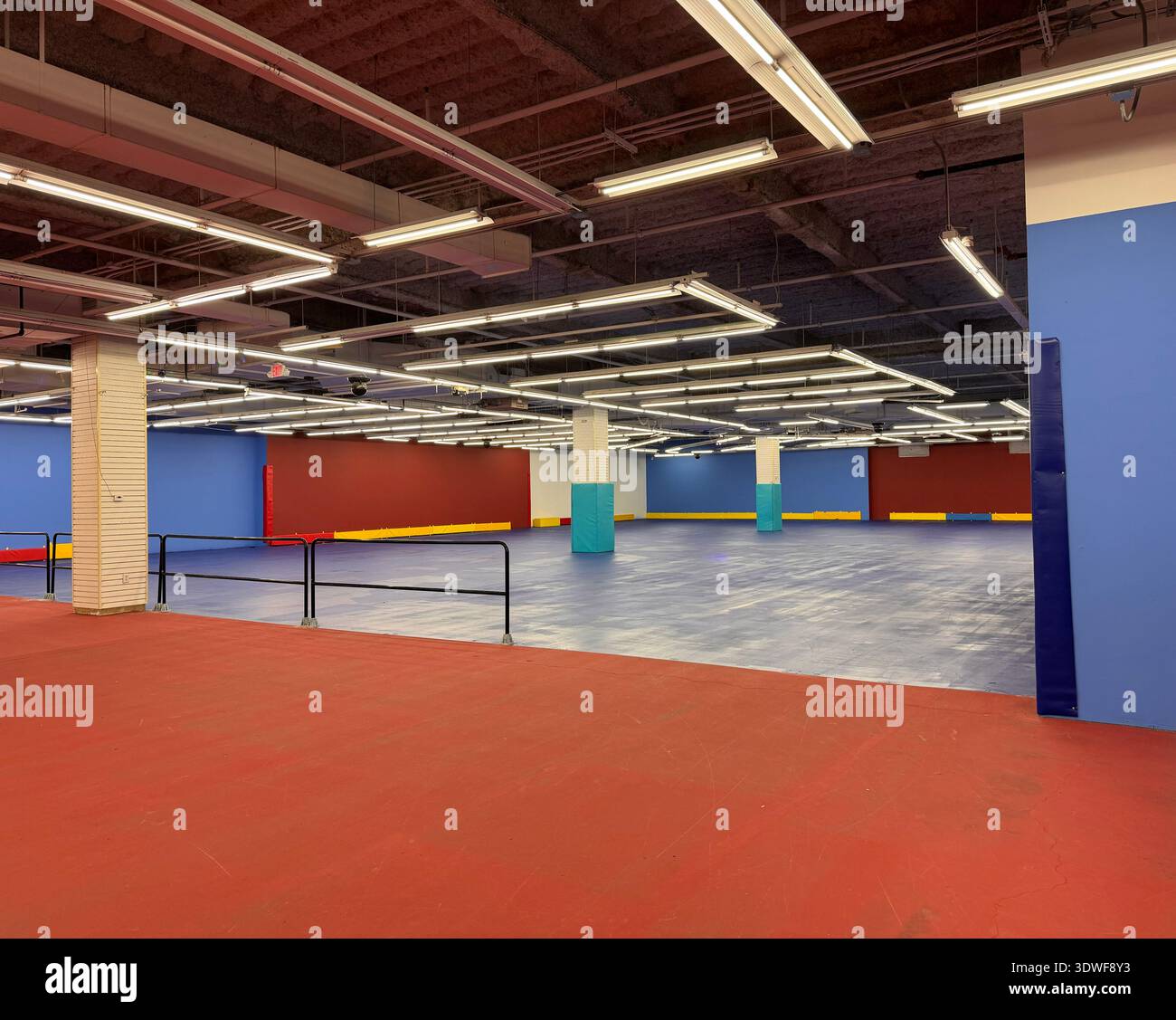 Empty indoor roller rink with colorful walls and fluorescent ceiling lights, wide open skating floor and railings. - Smartphone Captured Stock Image