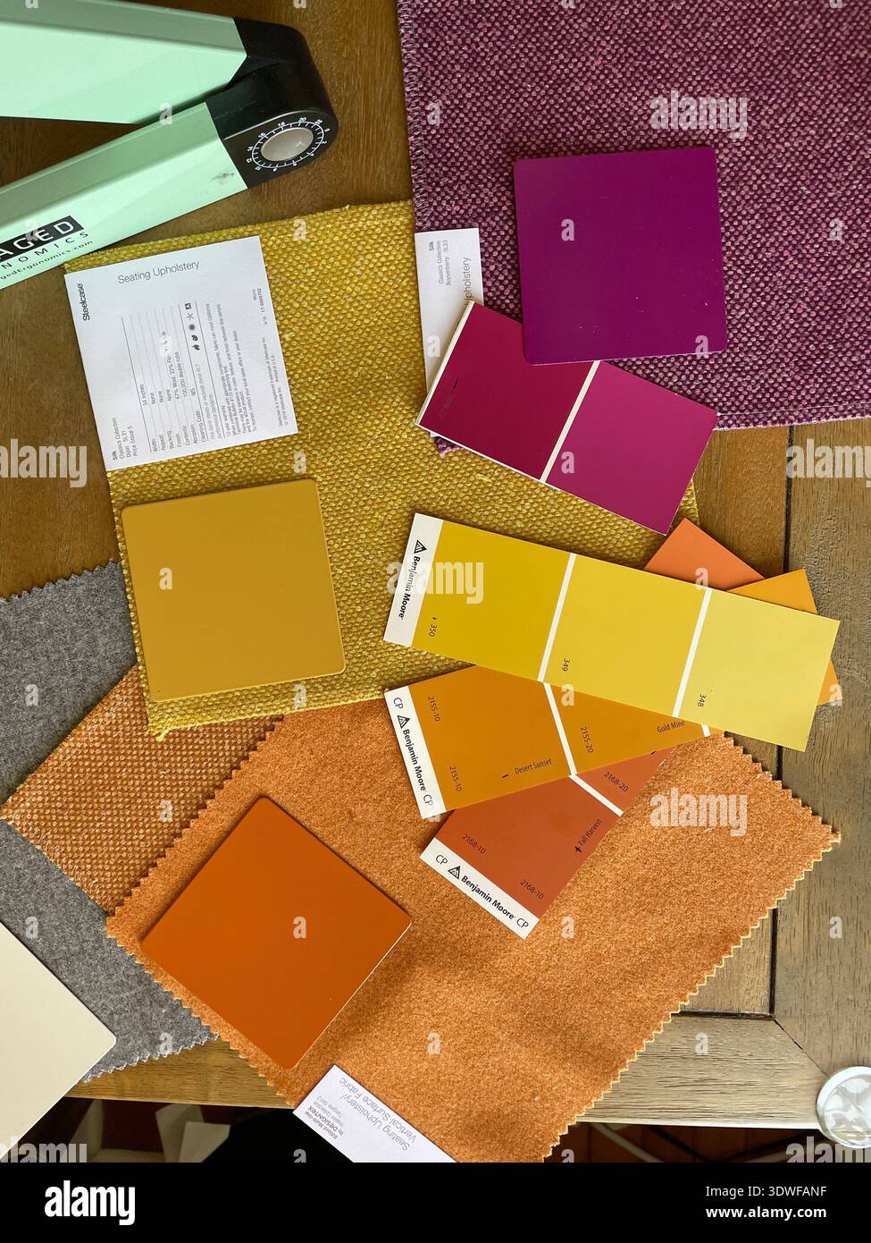 Flat lay of colorful fabric swatches and paint sample cards on a table, with Pantone chips for interior design and graphic designer color planning. - Smartphone Captured Stock Image