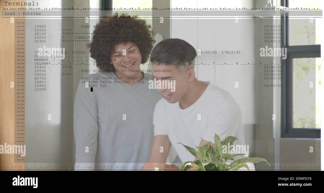 Leaning two men studying code on table at home office, wearing shirts with terminal overlay Stock Photo