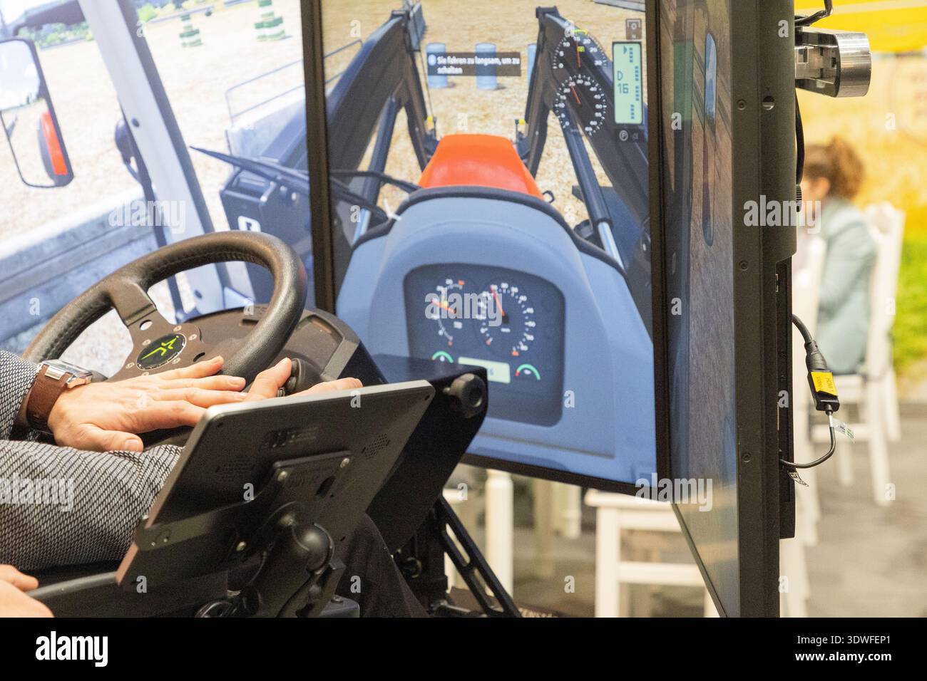 Berlin, Germany - January 24, 2025: . User is operating a tractor simulator with digital display showing controls and environment Stock Photo