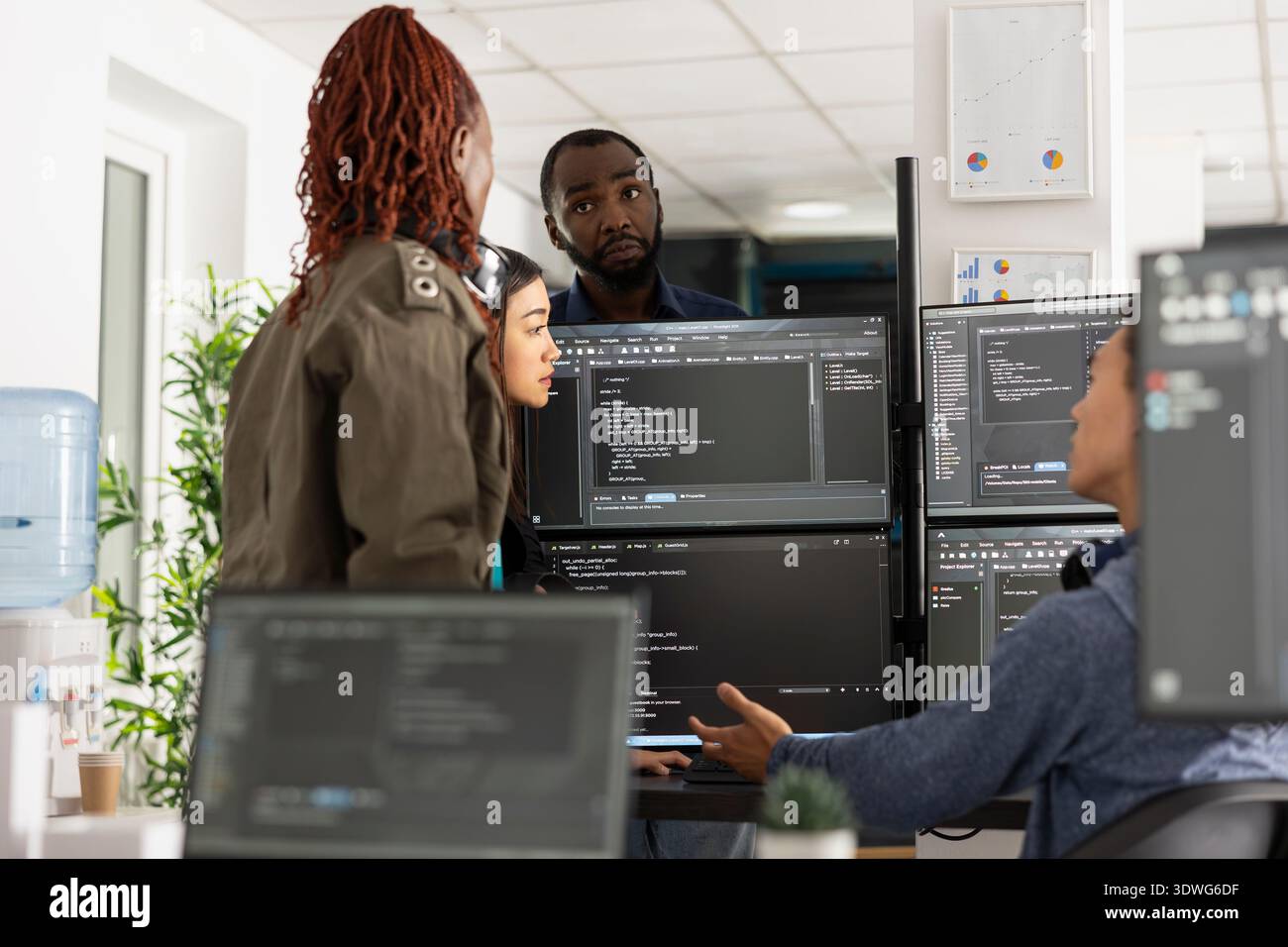 Multiethnic individuals analyzing code on multiple monitors, planning on improving frontend interface for clients. Professional team of developers working on web development project. Stock Photo