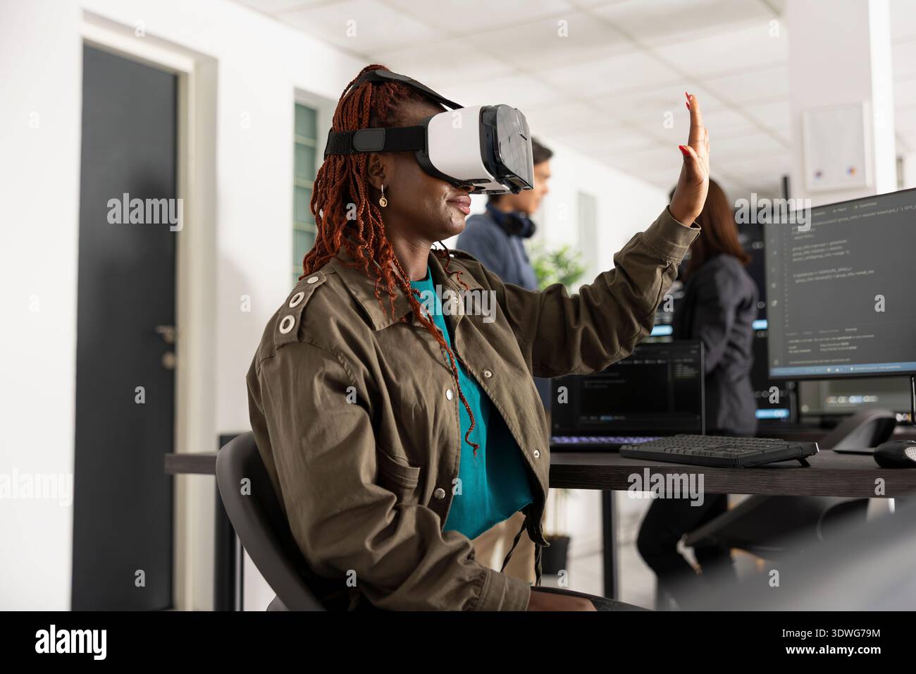 African american developer uses vr glasses to navigate 3D coding interface. Black woman works at innovative company, analyzing software scripts and applying virtual technology for development projects Stock Photo