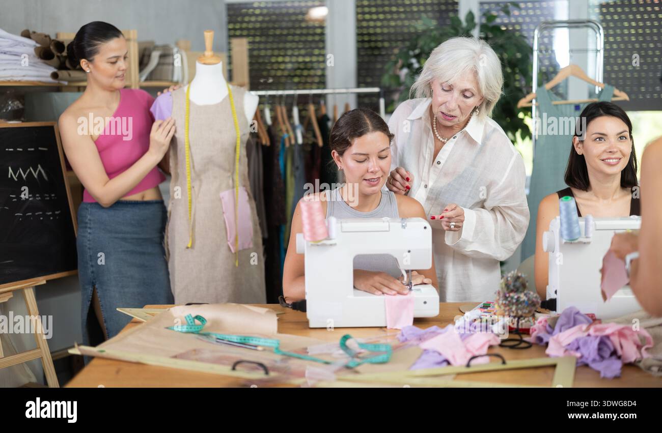 Sewing teacher guiding student during machine work Stock Photo