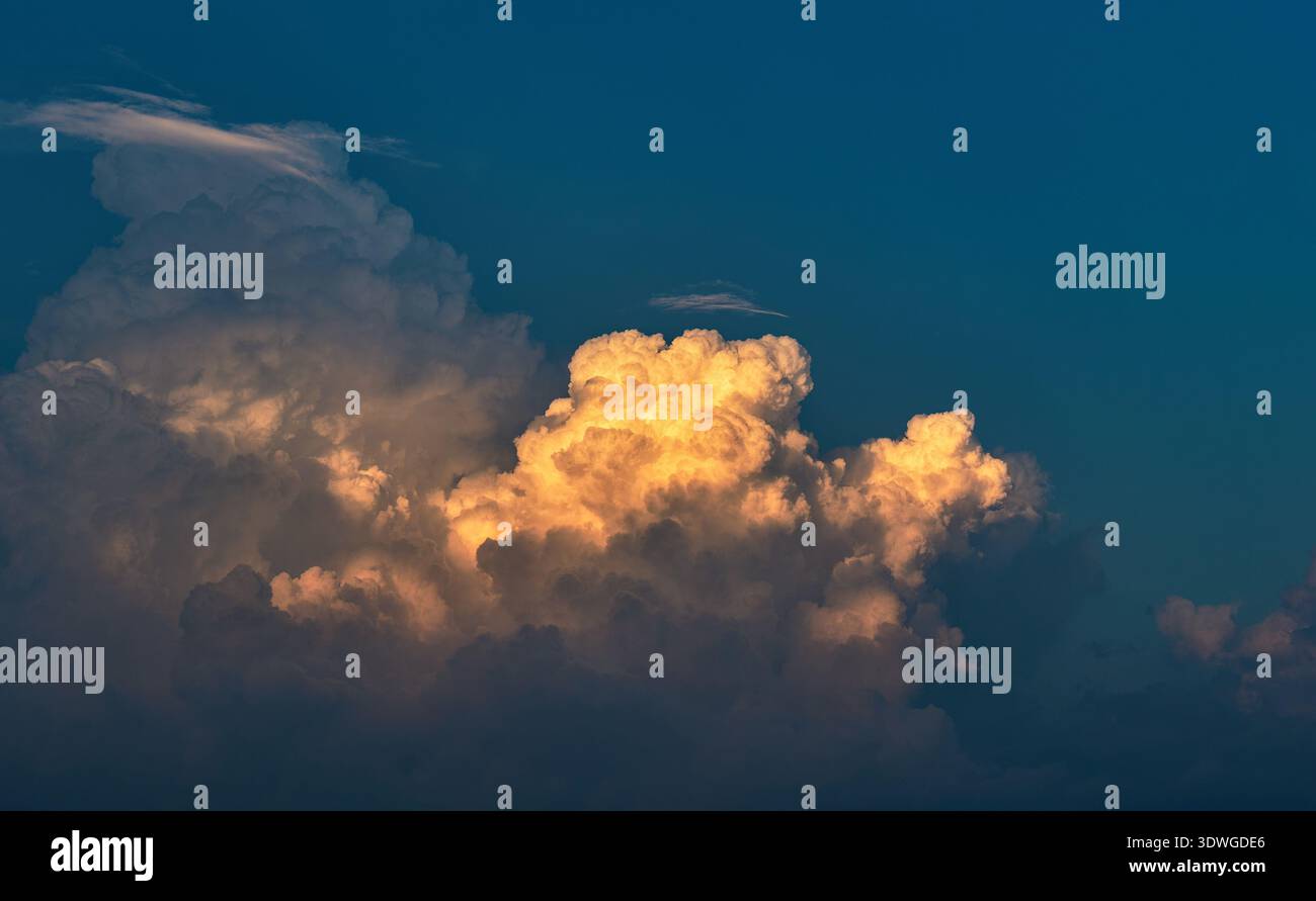 Dramatic Golden Light Clouds Against Deep Blue Sky Background Stock Photo