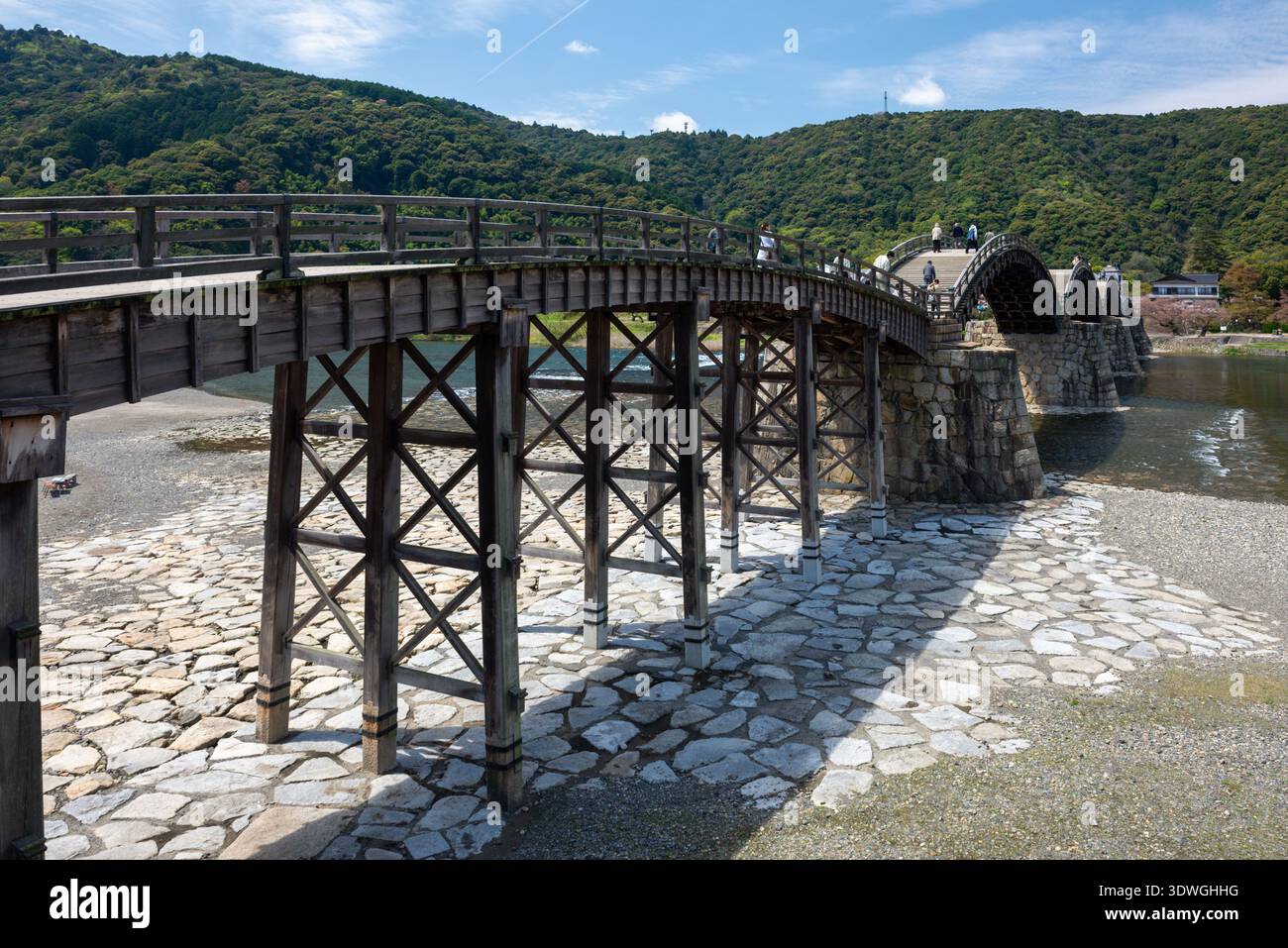 The iconic Kintai Bridge spans the river under a clear sky, showcasing ...