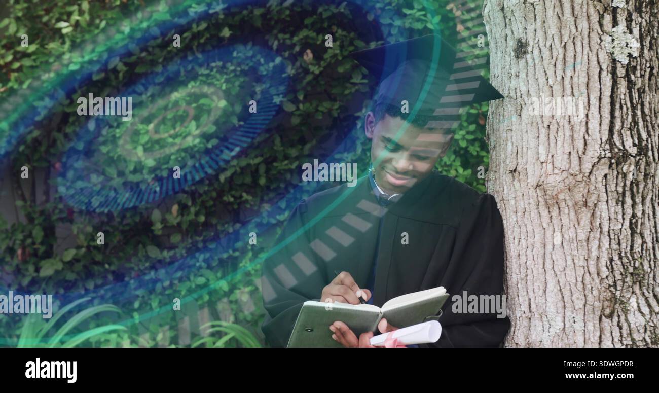 Writing man in black gown, cap, leaning against trunk on campus holding diploma, pad, teal overlay Stock Photo
