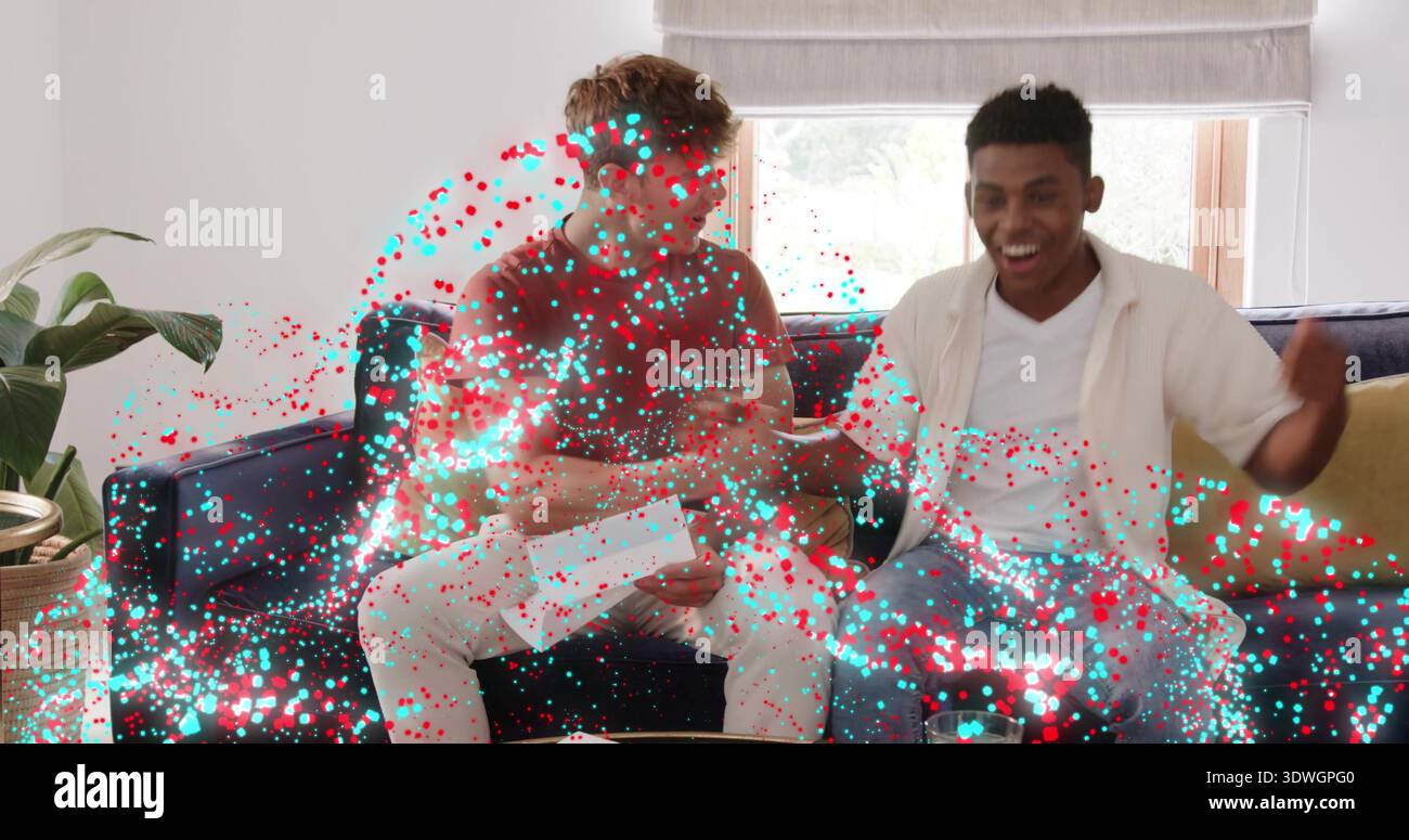 Holding envelope, men in brown, white shirts on sofa at home, other cheering amid confetti effect Stock Photo