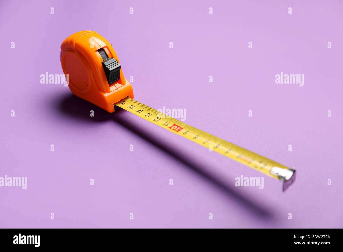 Orange measuring tape on violet background, closeup Stock Photo