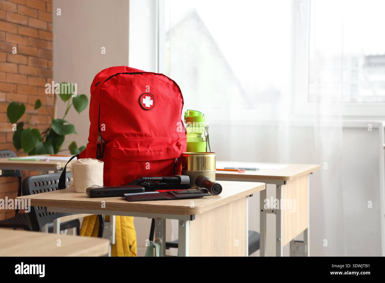 Emergency backpack with necessities on desk in classroom Stock Photo