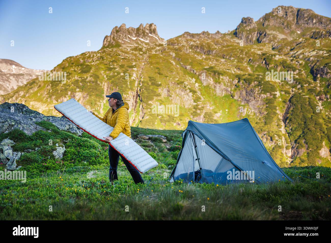 Camping in Alps mountain with tent and sleeping mat. Hiker preparing camp for night under peaks in austrian mountains during summer trekking Stock Photo