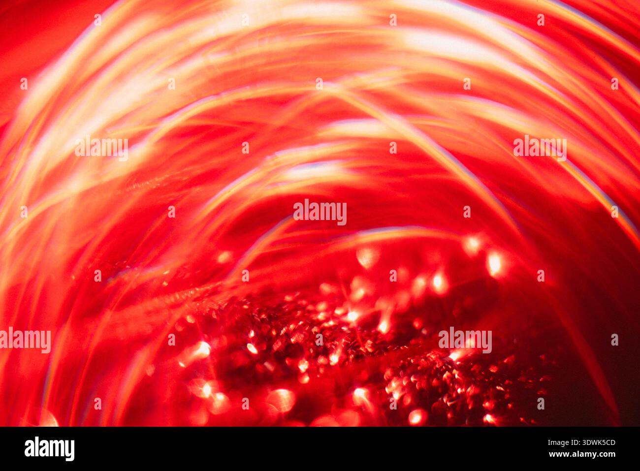 Abstract image featuring swirling red light patterns and reflections, with glimmering particles creating a vibrant and dynamic visual effect Stock Photo