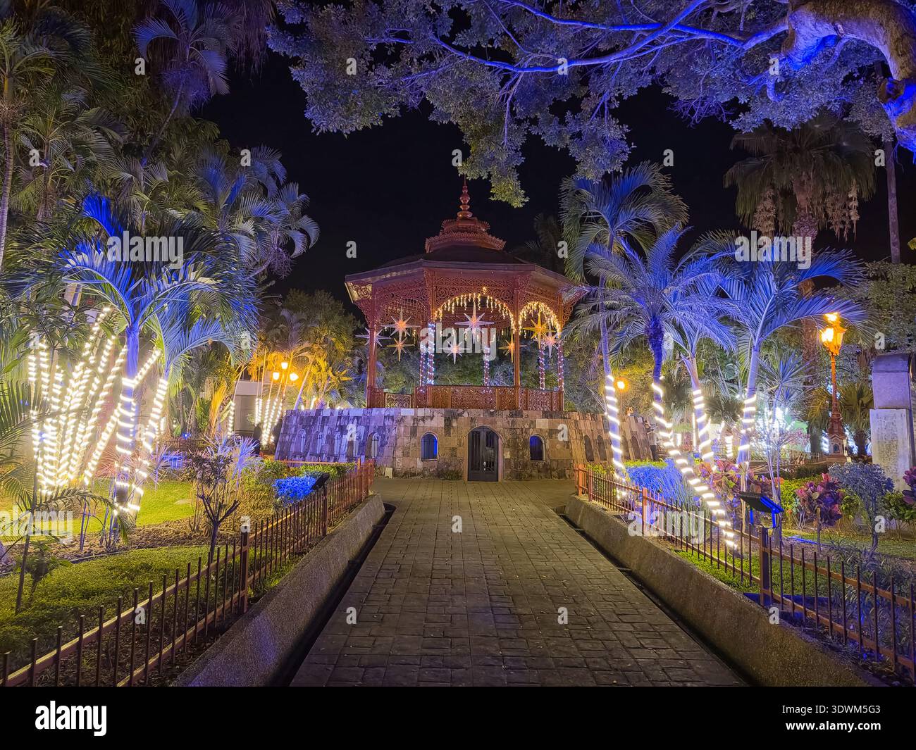 A park with a gazebo and a fountain. The fountain is lit up and the ...