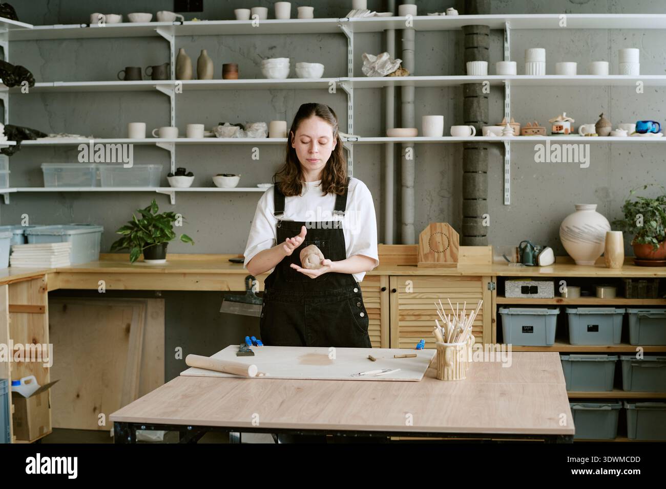 Young Adult Woman Shaping Clay While Working in Ceramics Studio Stock Photo