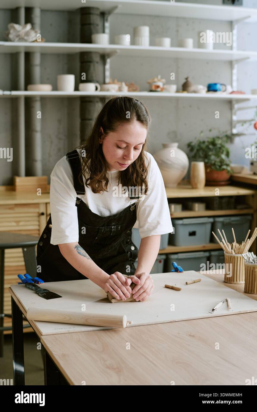 Young Adult Woman Shaping Clay While Working in Creative Studio Stock Photo