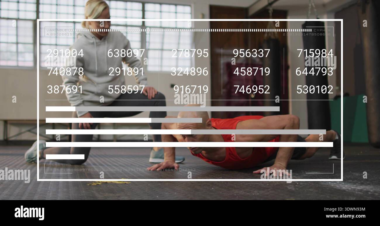 Performing man red tank top doing push-ups on rubber gym floor, trainer gray hoodie squatting, HUD Stock Photo