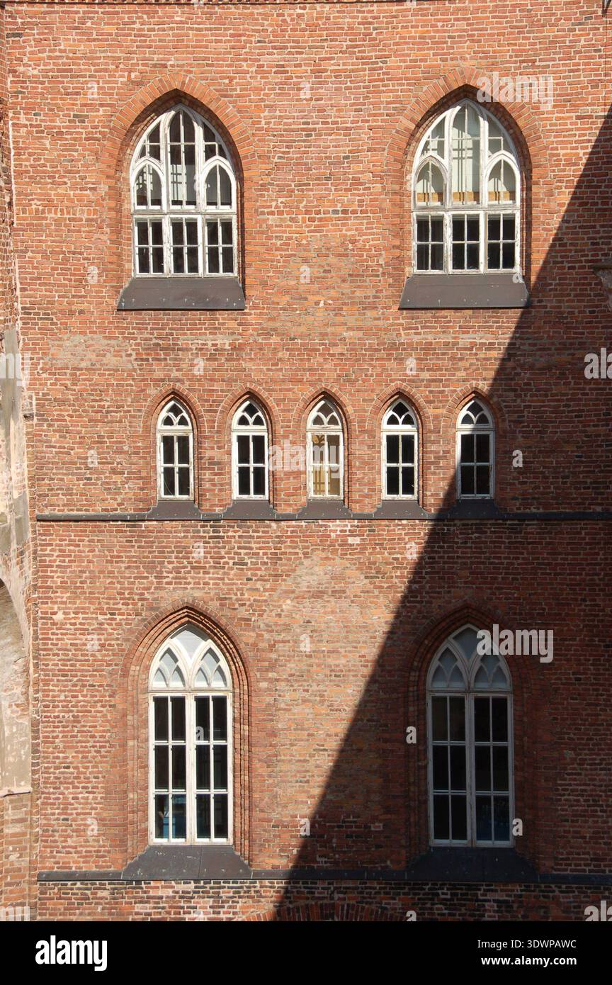 Gothic-style arched windows on a historic red brick church wall in ...