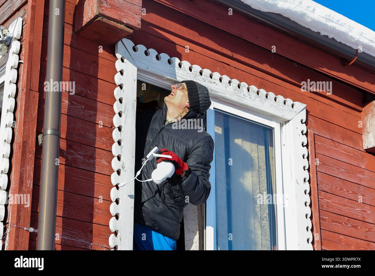 Farmer chooses place for dome camera surveillance on outer wall of rural house. Stock Photo