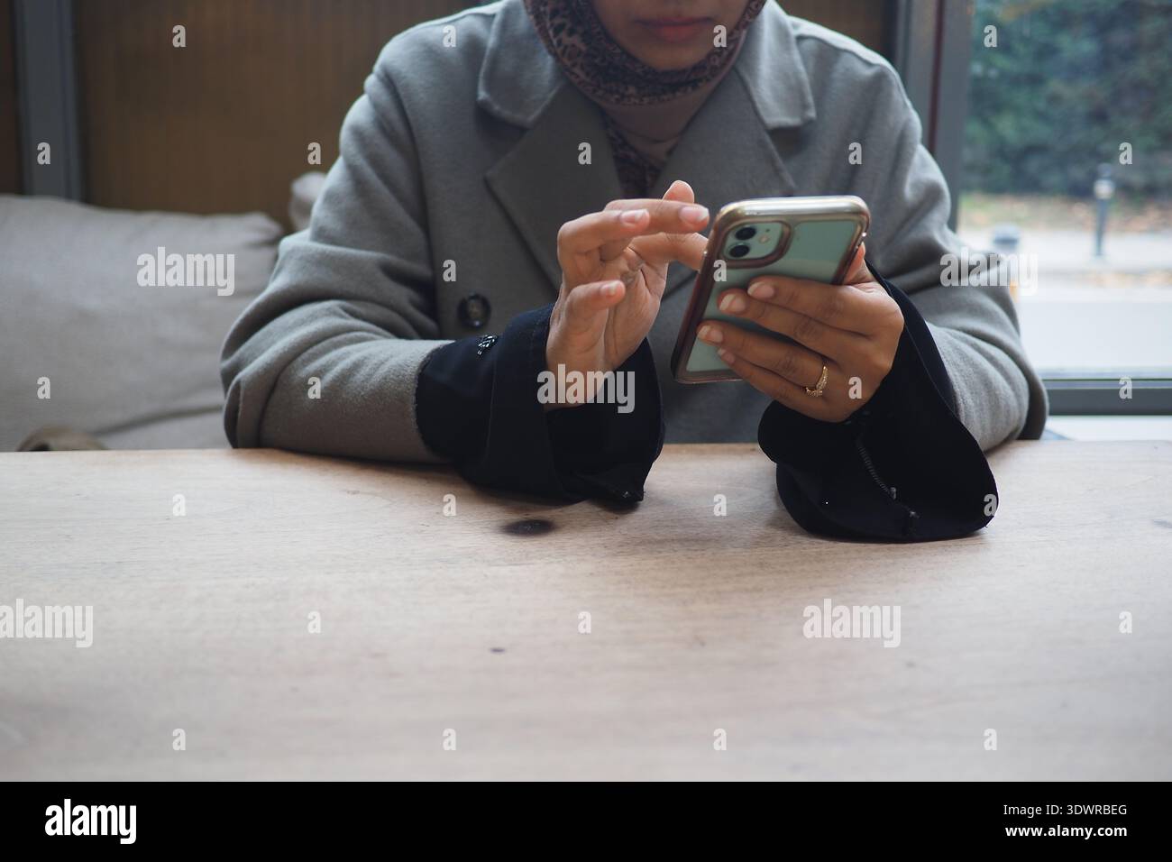 Woman using phone at a table in a cafe Stock Photo