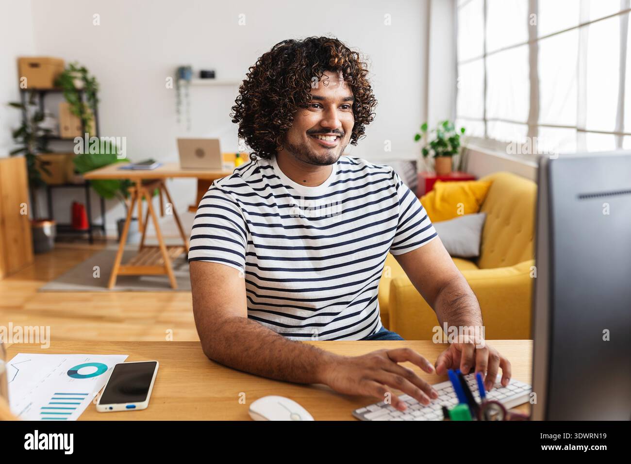 Young Indian man working on desktop computer at home office Stock Photo