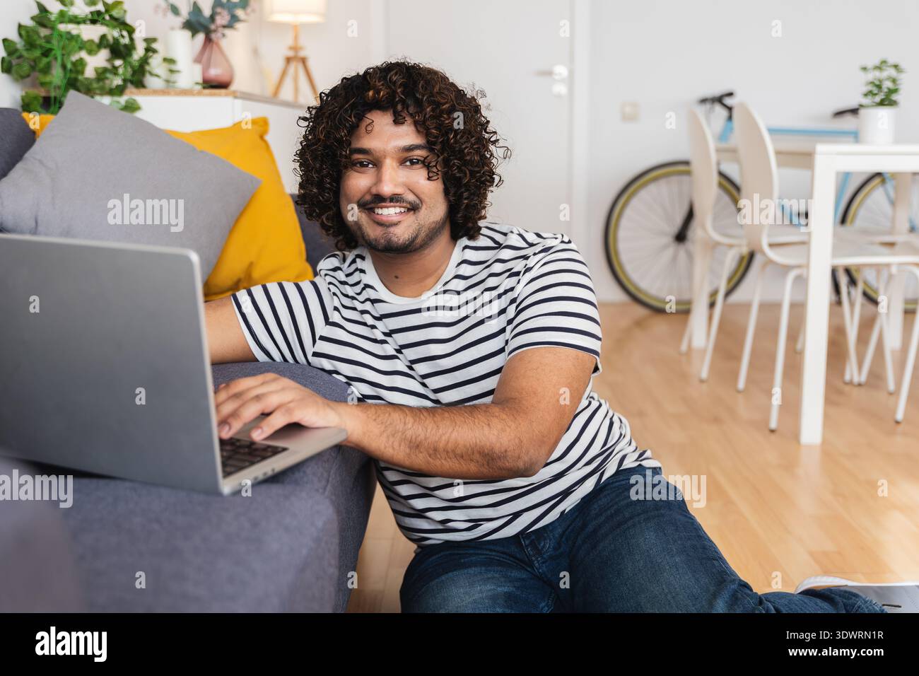 Young Indian man using laptop on sofa at home Stock Photo