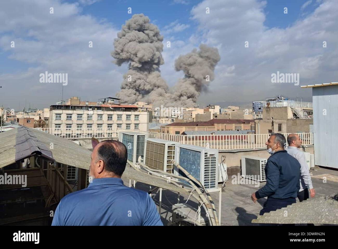People watch as smoke rises on the skyline after an explosion in Tehran, Iran, Saturday, Feb. 28, 2026.(AP Photo) Stock Photo