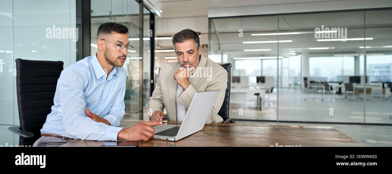 Two busy business men working using laptop computer in office thinking on data. Stock Photo